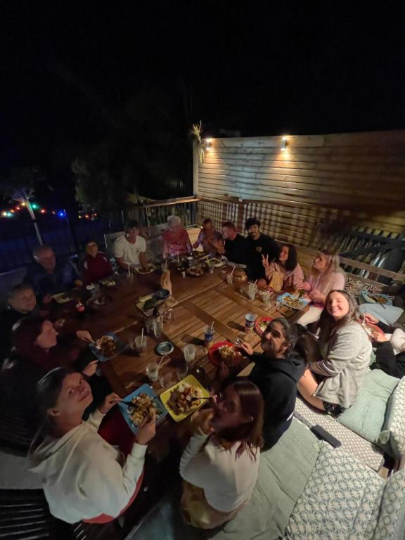 eine Gruppe von Menschen, die um einen großen Holztisch sitzen in der Unterkunft Dodo House auberge de jeunesse in Saint-Leu