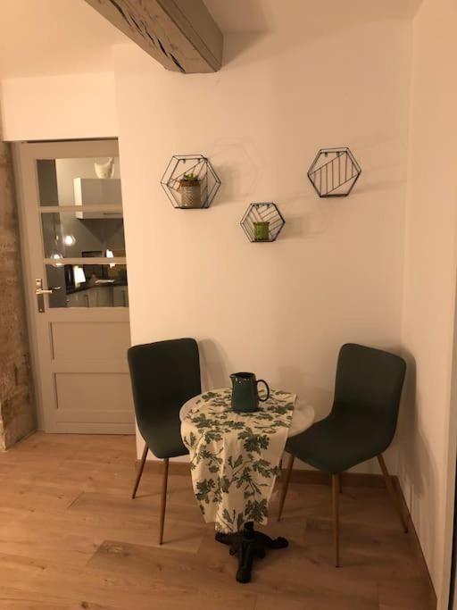 a table with two chairs and a table with a cup on it at Nuits centre : superbe gîte rénové et climatisé in Nuits-Saint-Georges