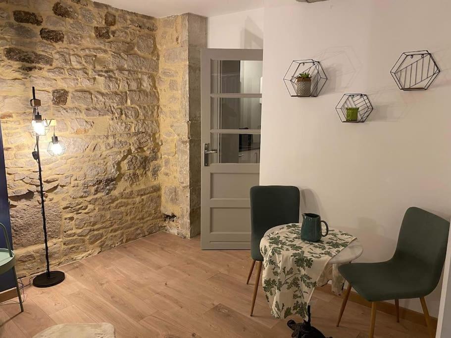 a room with a table and chairs and a brick wall at Nuits centre : superbe gîte rénové et climatisé in Nuits-Saint-Georges