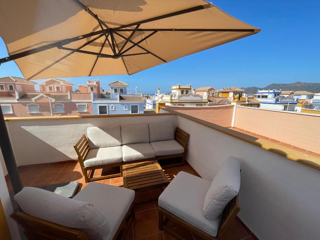einen Balkon mit 2 Stühlen und einem Sonnenschirm in der Unterkunft Villa Lilibella in San Juan de los Terreros