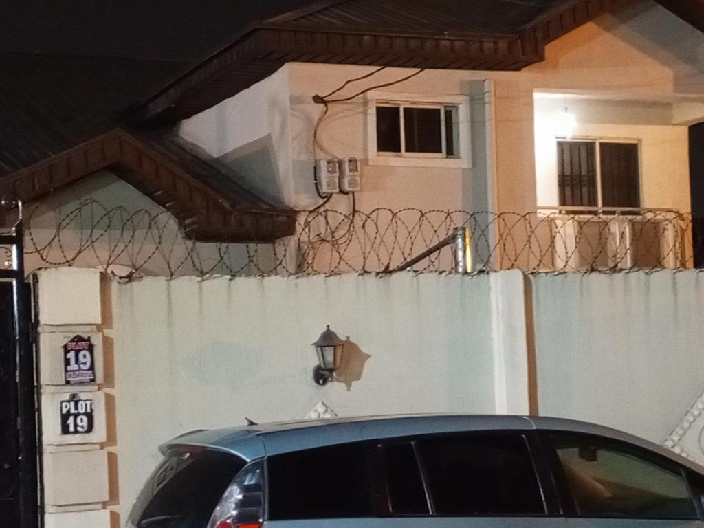ein Auto, das vor einem Haus mit einem Zaun parkt in der Unterkunft Treasure apartment in Lagos