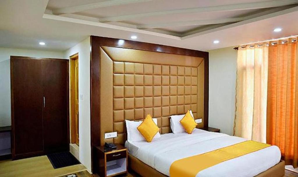 um quarto com uma cama grande e almofadas amarelas em FabHotel Whistling Winds em Manali