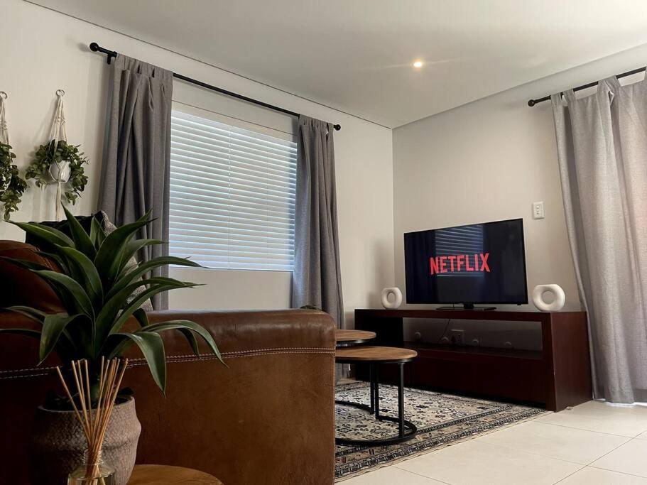 uma sala de estar com um sofá e uma televisão em Cosy Comfort Guest Suit em Durban