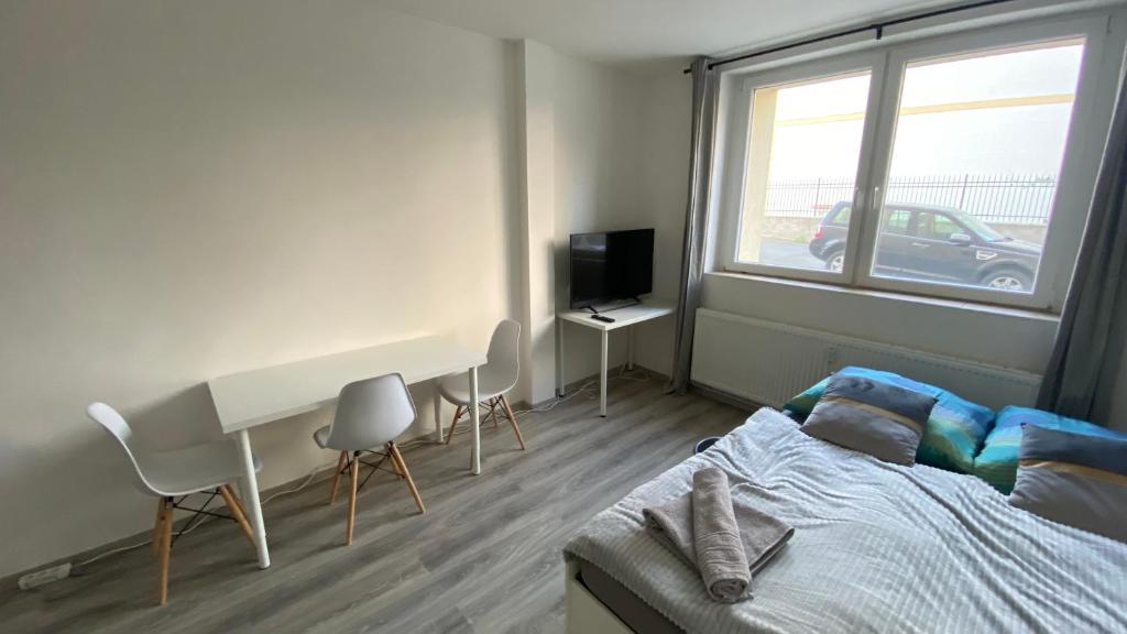 Schlafzimmer mit einem Bett, einem Schreibtisch und einem Fenster in der Unterkunft NOVÝ krásný apartmán - 15 min od centra in Prag