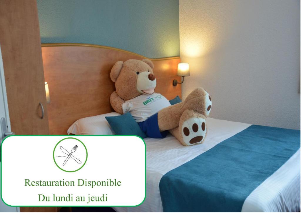 un ours en peluche assis au-dessus d'un lit dans l'établissement BRIT HOTEL Caen Hérouville, à Hérouville-Saint-Clair