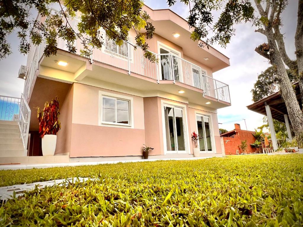 una casa rosa con un césped verde delante de ella en Los Hermanos Residencial, en Florianópolis