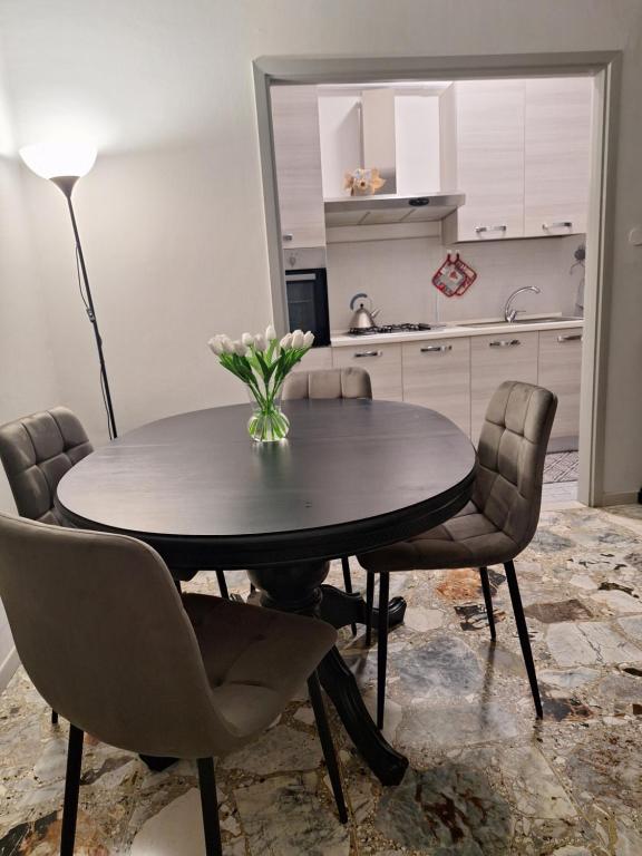 una mesa de comedor con sillas y un jarrón de flores. en L'airone apartment, en Casale Monferrato