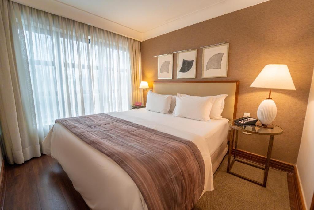 um quarto de hotel com uma cama grande e uma janela em George V Alto De Pinheiros em São Paulo