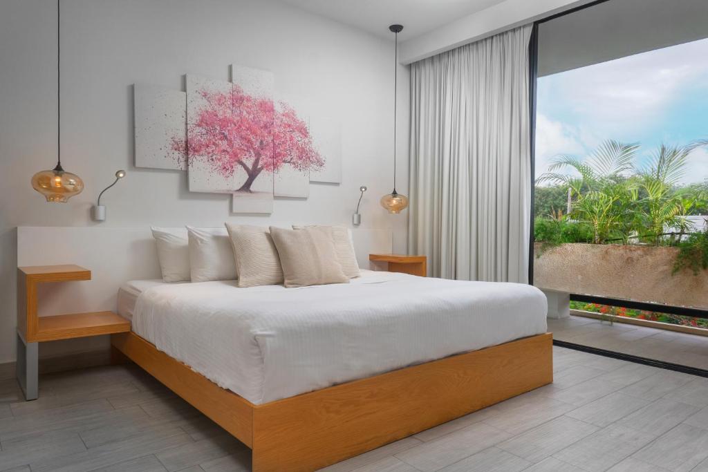 a bedroom with a large bed with a tree on the wall at Opal Suites Apartments in Playa del Carmen