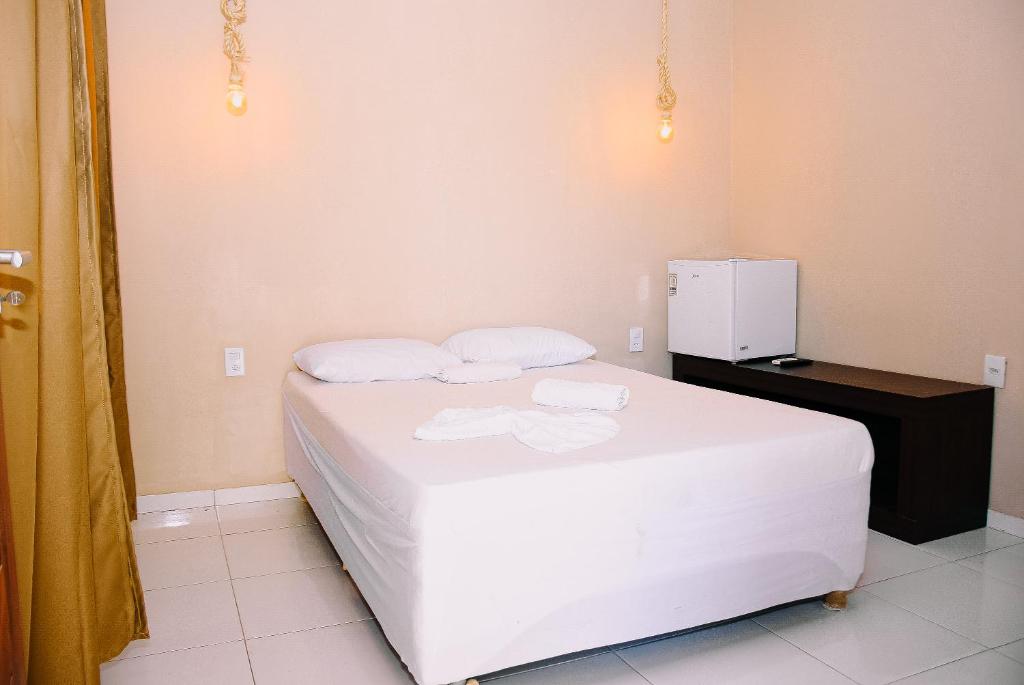 a bedroom with a white bed with two towels on it at Pousada do gaúcho in Barreirinhas