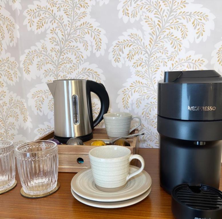 a coffee maker and cups on a wooden table at Old Town House by Ezestays in Margate