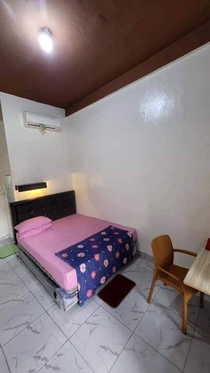 Dormitorio pequeño con cama rosa y silla en PENGINAPAN 77, en Pulupanda