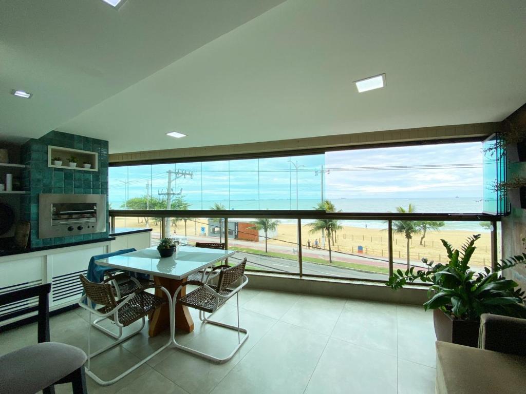 ヴィラ・ヴェーリャにあるApartamento De frente ao mar, linda varanda com churrasqueiraのキッチン(テーブル、椅子付)、大きな窓が備わります。