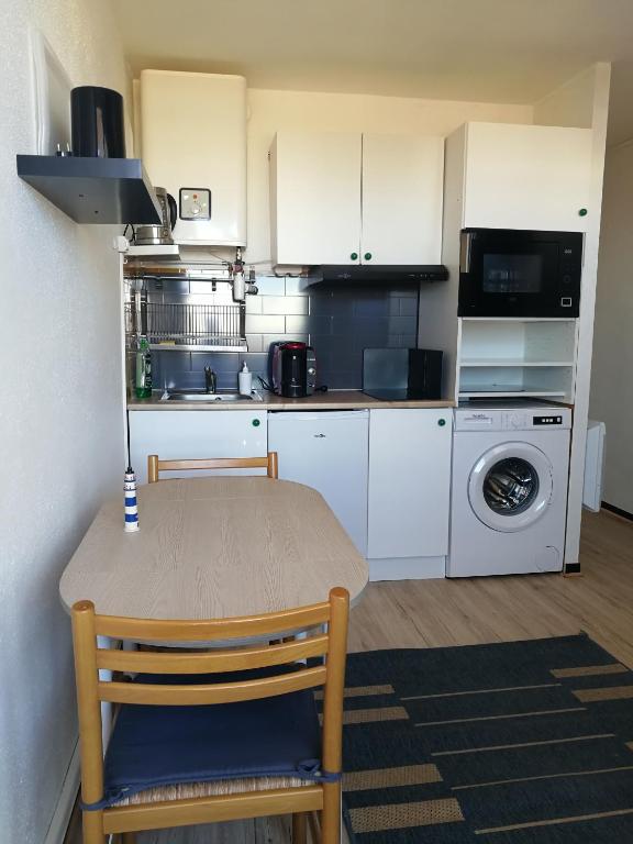 une cuisine avec des placards blancs, une table et un lave-linge dans l'établissement Agréable studio 50m de la plage, à Canet