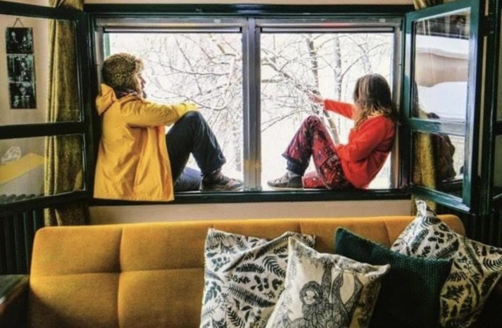 two people sitting on a window sill looking outside at Private Mountain House in Laklouk - 1 Bedroom in Ad Dā‘ūq