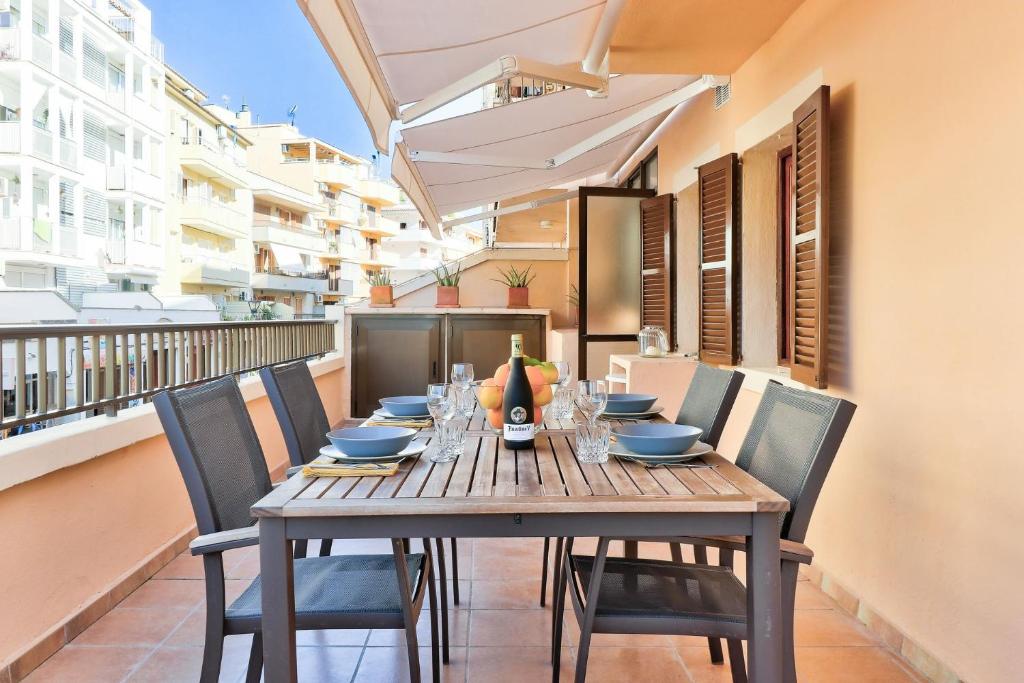 a wooden table with chairs and a bottle of wine on a balcony at Apartamento NICE4YOU by Rentallorca in Port d'Alcudia