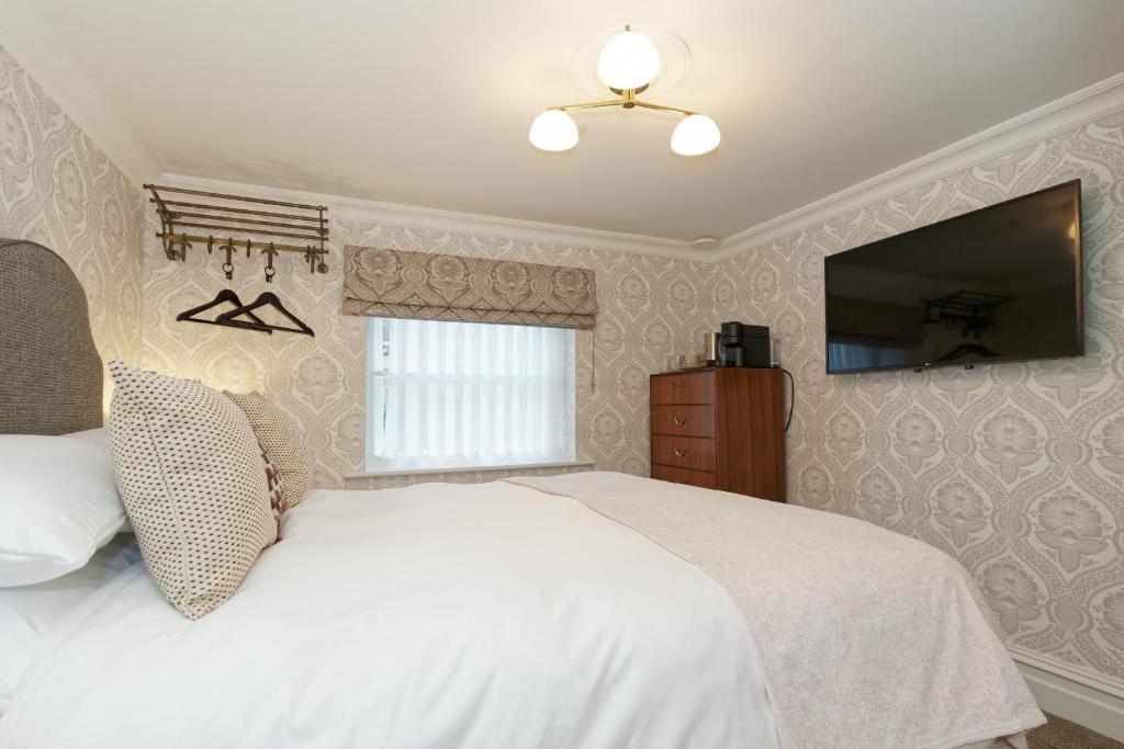 a bedroom with a white bed and a flat screen tv at Old Town House by Ezestays in Margate