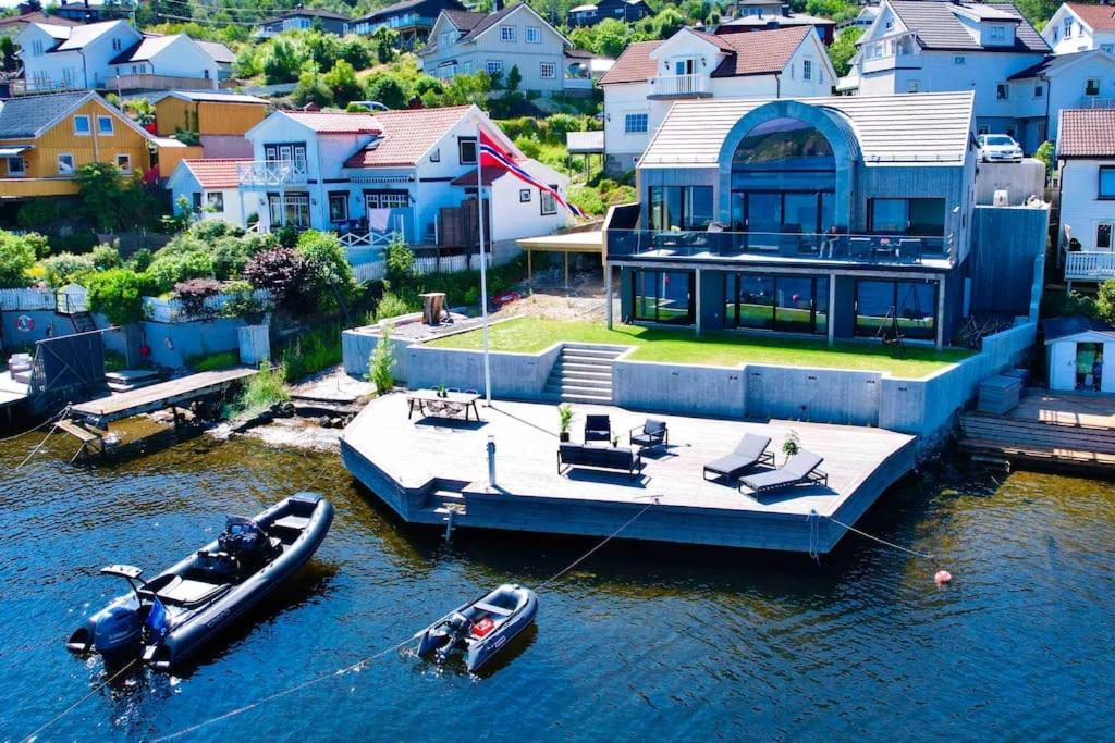 a large house with a boat docked in the water at Unikt feriested med stor privat brygge in Bamble