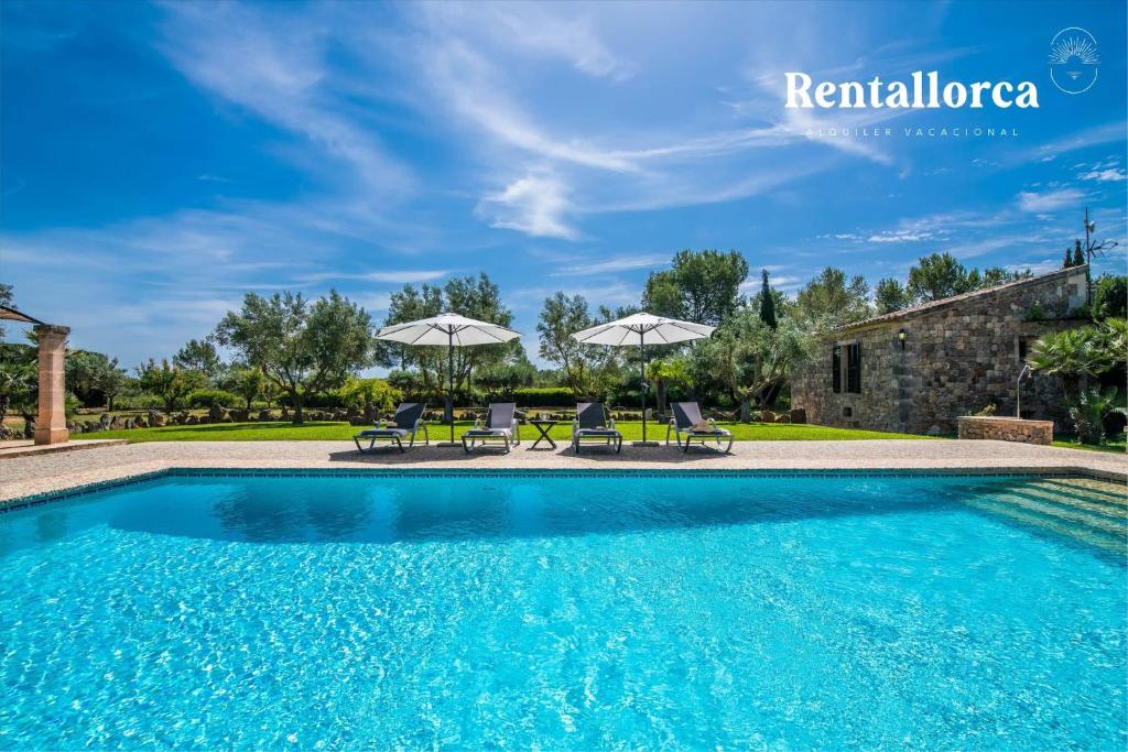 a pool with chairs and umbrellas in front of a house at Finca Son Guillotet by Rentallorca in Maria de la Salut