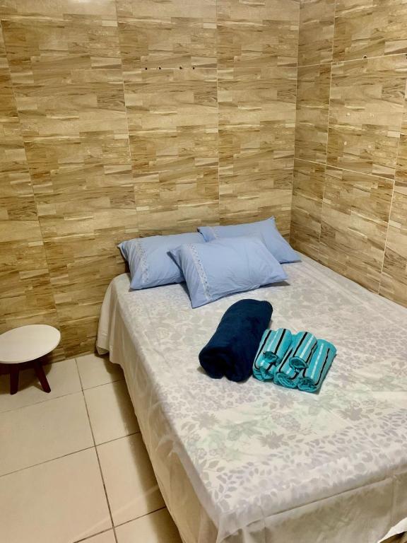 a bed with two blue pillows on top of it at Quarto privativo Caruaru fácil acesso para o pátio de eventos e feira da sulanca in Caruaru