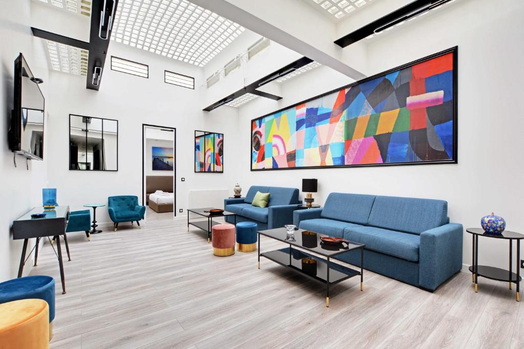 un salon avec des canapés bleus et un grand tableau dans l'établissement Superb apartment with hammam -4BR-12P- Bastille, à Paris