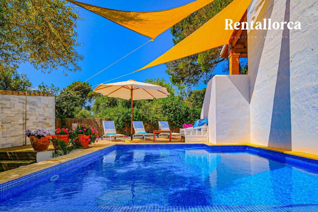 ein Pool mit einem Sonnenschirm, 2 Stühlen und einem Sonnenschirm in der Unterkunft Cas Predi by Rentallorca in Can Picafort