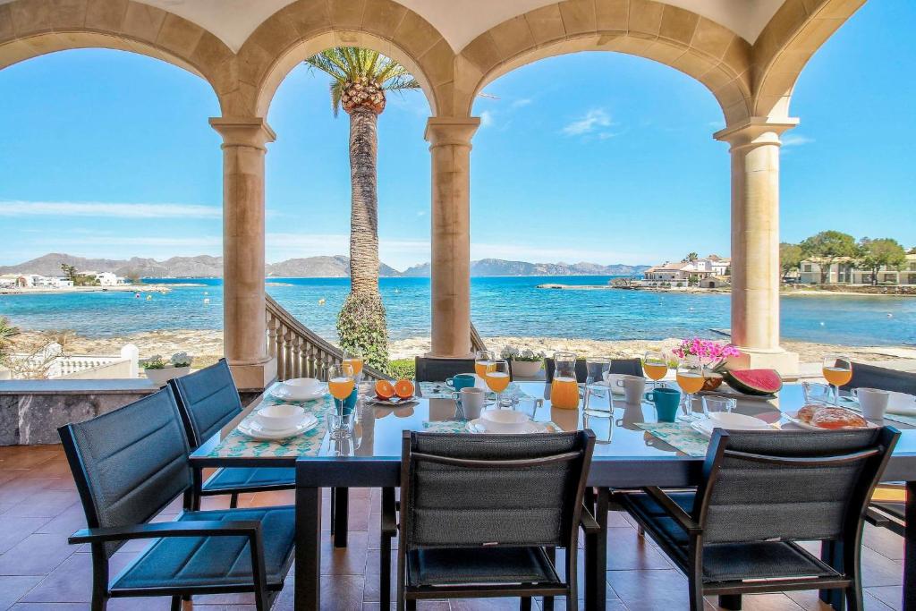 een eetkamer met een tafel en stoelen en de oceaan bij Villa Can Siulet by Rentallorca in Alcudia