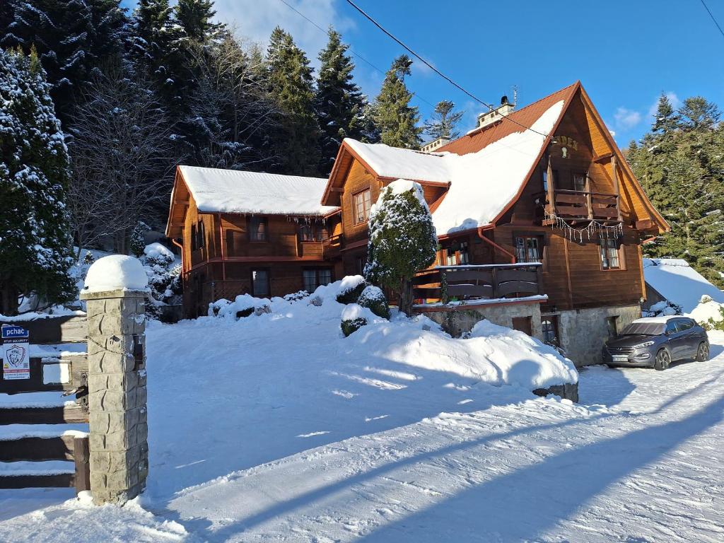 uma cabana de madeira na neve com um carro em Dom Gościnny Dudek em Krynica Zdrój