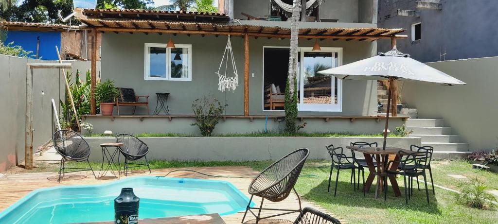 a patio with a table and chairs and an umbrella at Casa Mathia in Caraíva