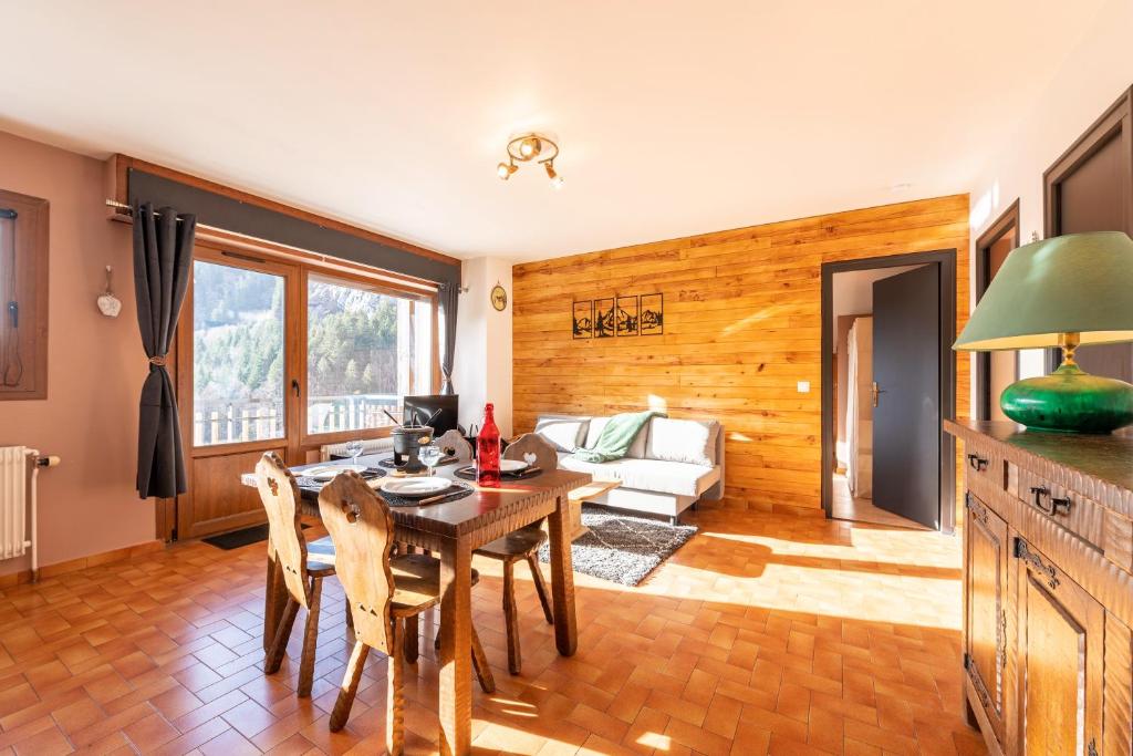 a dining room with a table and a couch at Le petit Schuss - A 10min des remontées mécaniques in La Giettaz