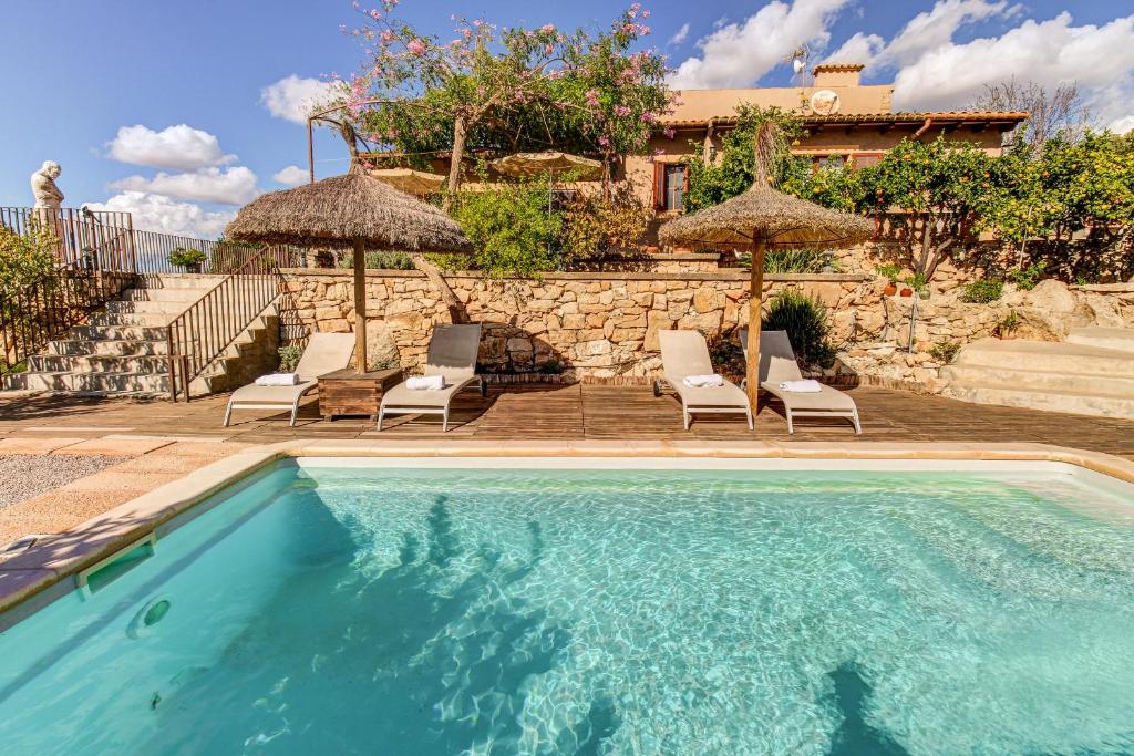 ein Pool mit Stühlen und Sonnenschirmen sowie ein Haus in der Unterkunft Son Cladera Bosch by Rentallorca in Manacor