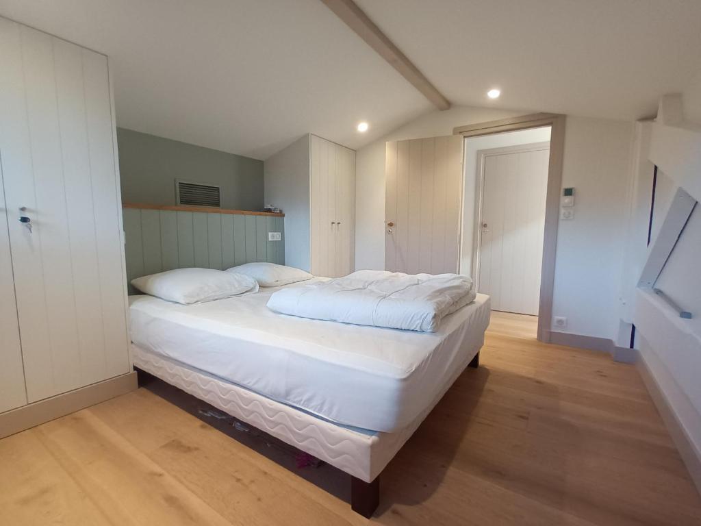 拉泰斯特德比克的住宿－Arcachon le Moulleau maison moderne 3 chambres climatisation - 250m de la plage，卧室配有一张带白色床单和枕头的大床。