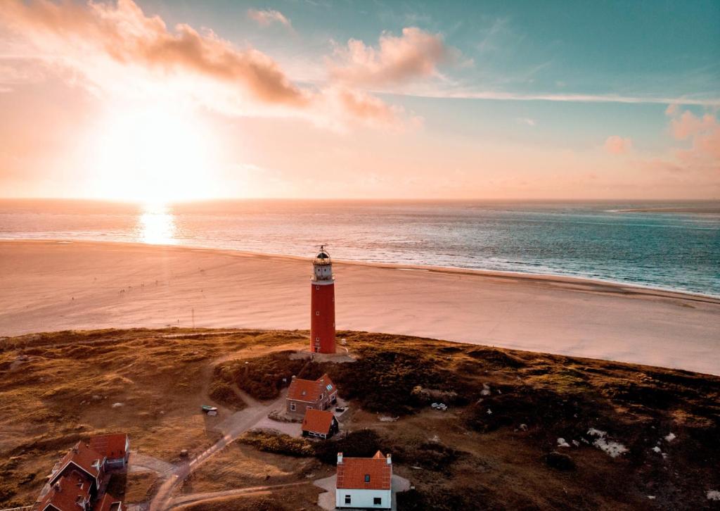 a lighthouse on the shore of a beach with the ocean at Puur Texels 9a in De Koog