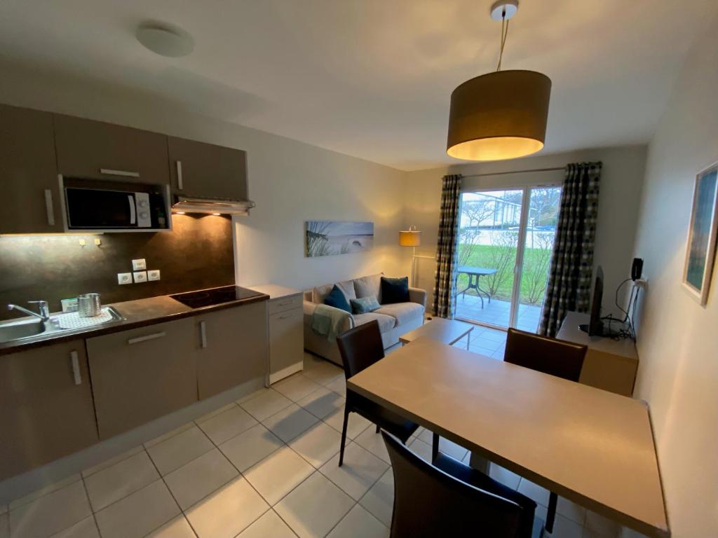 une cuisine et un salon avec une table et une salle à manger dans l'établissement Le Cabellou - Appt avec piscine commune, à Concarneau
