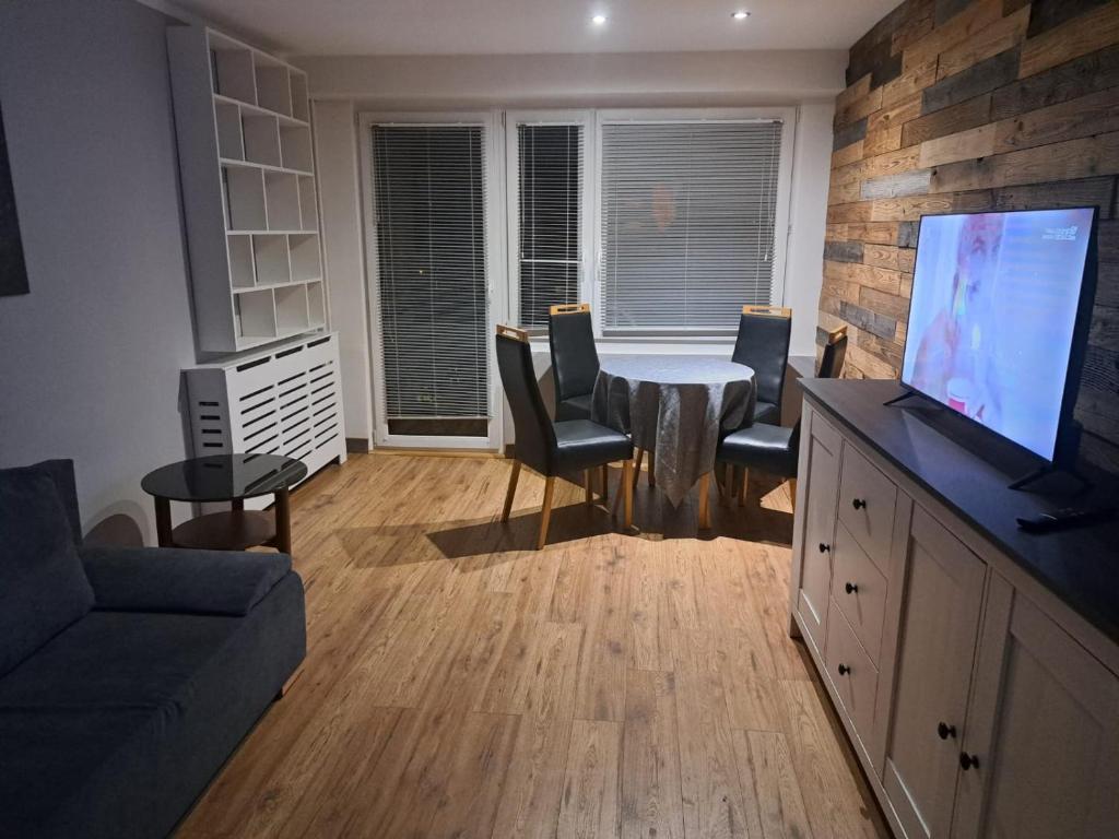 a living room with a table and chairs and a television at Apartament 3 pokoje in Słupsk