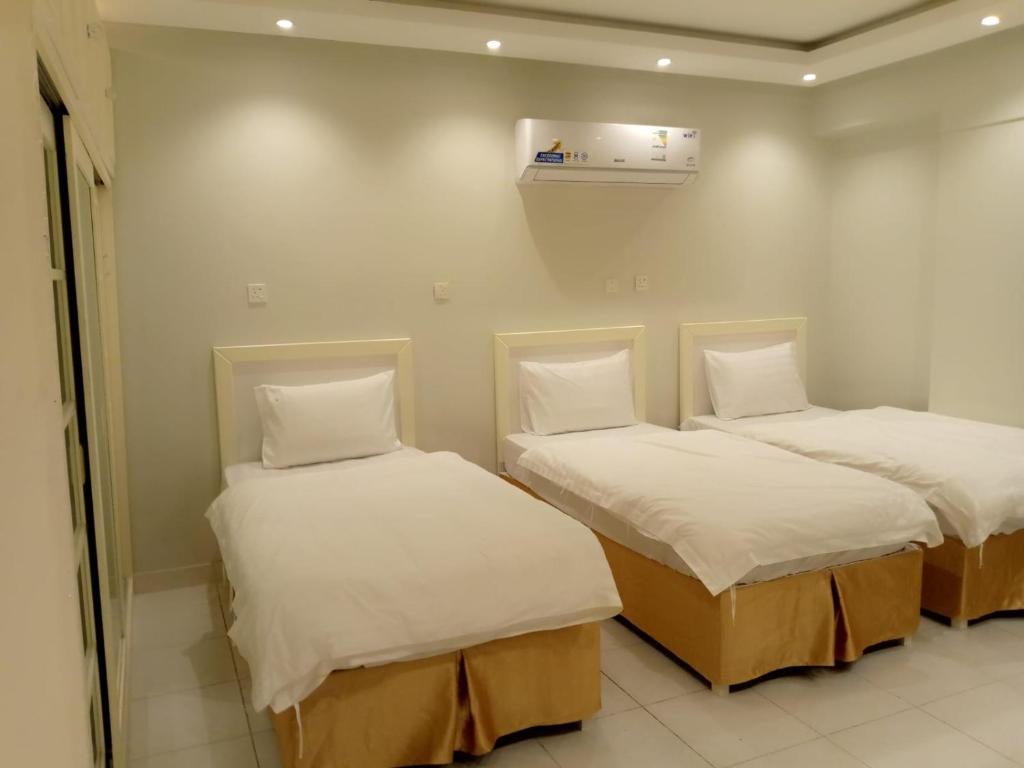 two beds in a room with white sheets and pillows at جودي للغرف الفندقية المتميزة in Al Khobar