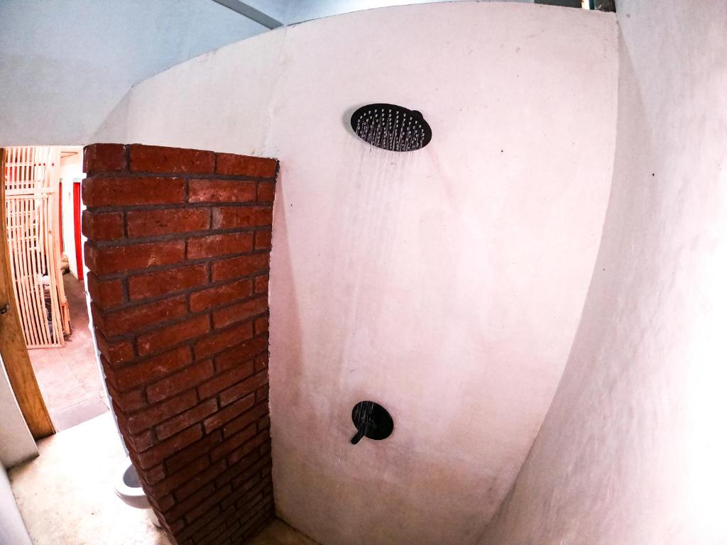 um chuveiro com uma parede de tijolos e um ralo em Maka Hostel em Oaxaca de Juárez