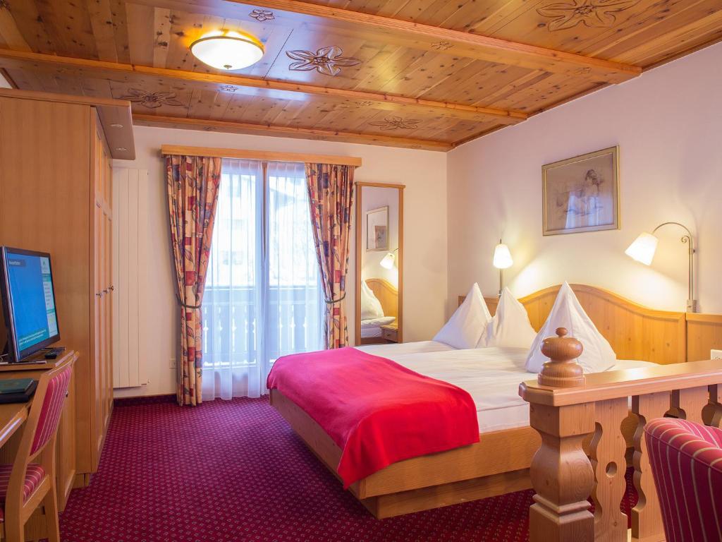a hotel room with a bed and a television at Alpenblick in Zermatt