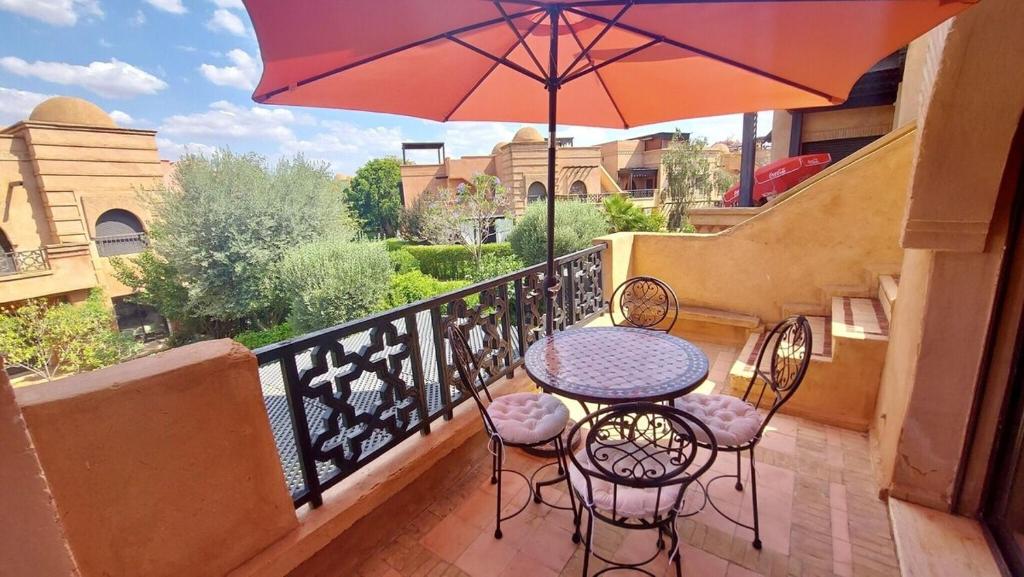 - un balcon avec une table, des chaises et un parasol dans l'établissement DIANA, à Marrakech