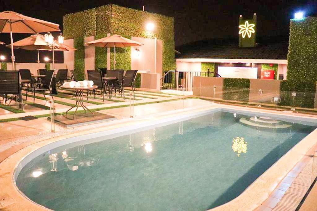 una piscina por la noche con mesas y sillas en بالم السكنية en Abha