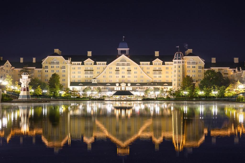 a large building with its reflection in the water at night at Disney Newport Bay Club in Chessy
