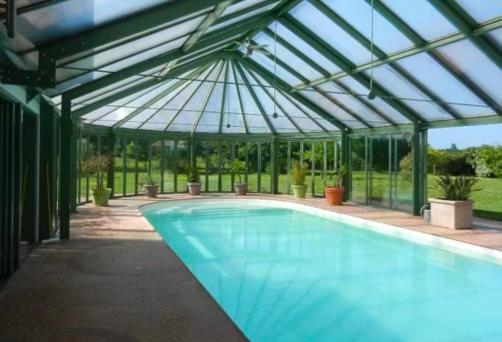 une piscine dans une serre avec un toit en verre dans l'établissement Domaine de la Haute Justerie - piscine & billard à l’orée des bois - Loire Valley, à Fondettes