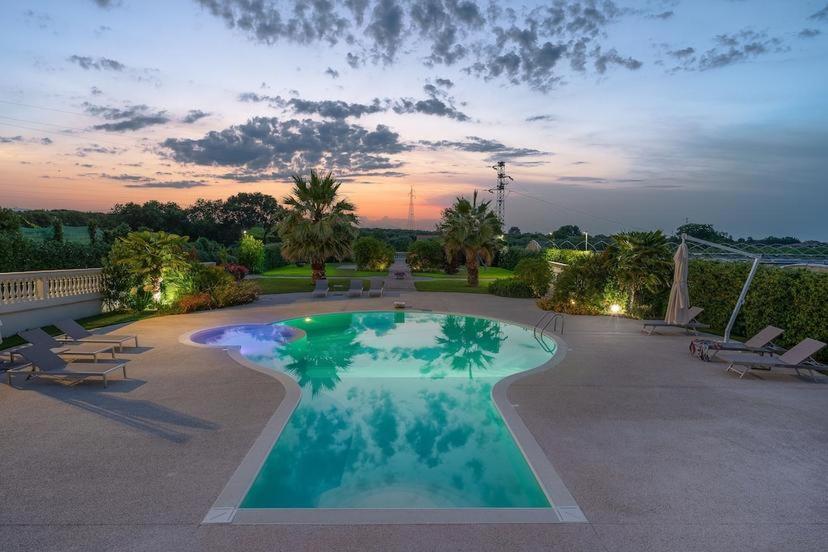 a large swimming pool with chairs and a sunset at Le Dimore di Giò in campagna in Ortona