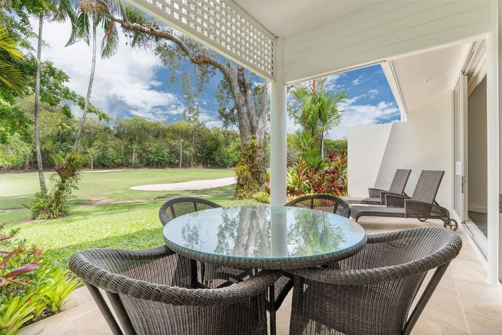 eine Terrasse mit einem Glastisch und Stühlen in der Unterkunft Tropical Resort-style Living on Mirage Golf Course in Port Douglas