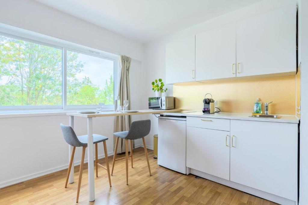 een keuken met witte kasten en een tafel en stoelen bij Croisé Laroche equipped studio! in Marcq-en-Baroeul