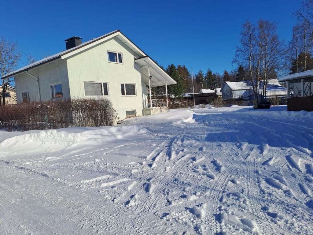 a snow covered driveway with a house in the background at Kalevala Home in Oulainen