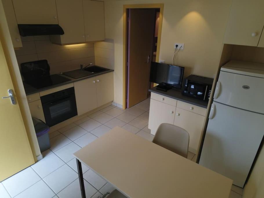 een kleine keuken met een tafel en een koelkast bij Appartement 27 Groix in La Bernerie-en-Retz