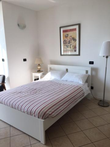 um quarto com uma cama branca e um cobertor listrado em flat in Padova center em Pádua