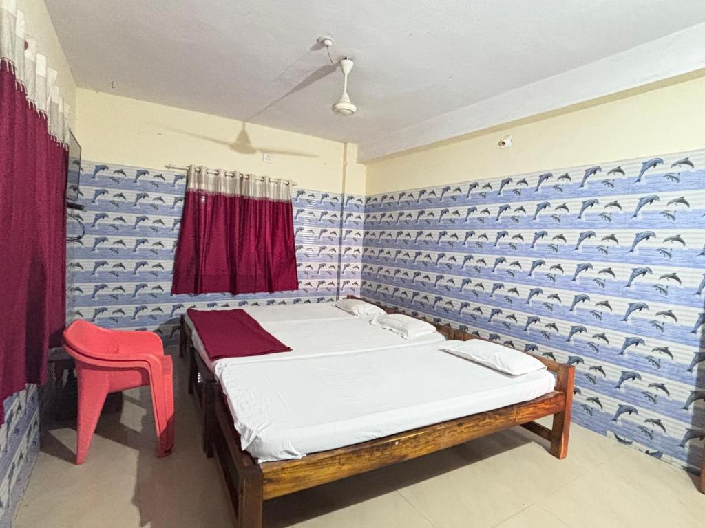 Cette chambre comprend deux lits et un fauteuil rouge. dans l'établissement Naika Lodge, à Māvalli