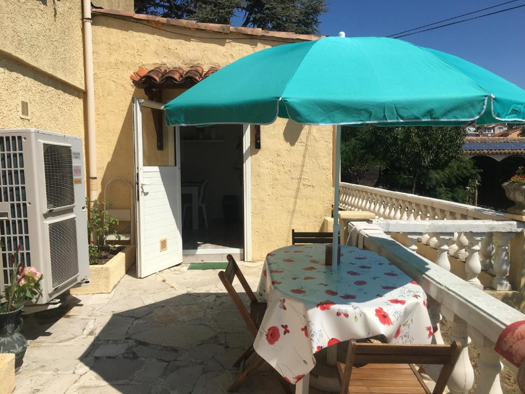 einen Tisch und einen Stuhl unter einem Schirm auf einer Terrasse in der Unterkunft villa les mimosas in Antibes